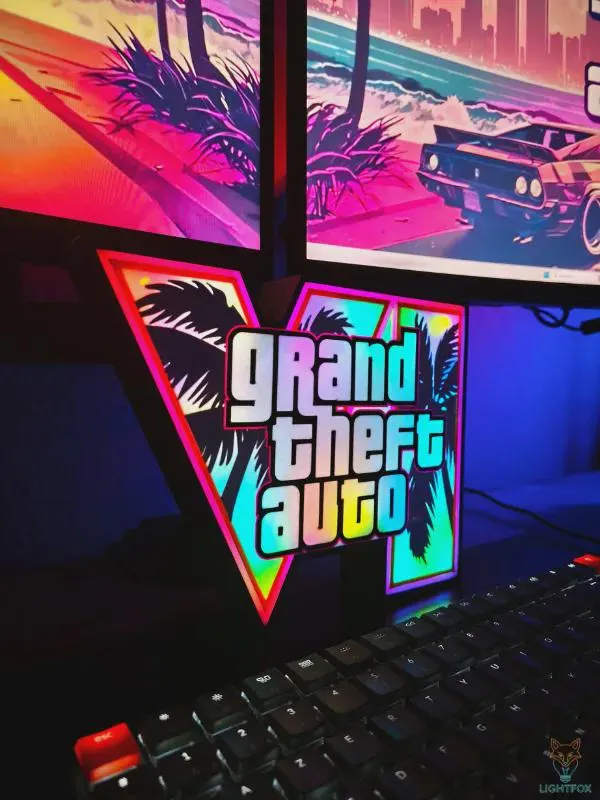 Neon-lit gaming desk with a keyboard, monitors and glowing decor